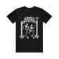 Comfort Colors black t-shirt featuring a white graphic of two skeletons dancing under a gothic arch, with one skeleton wearing a sign that reads KICK ME.